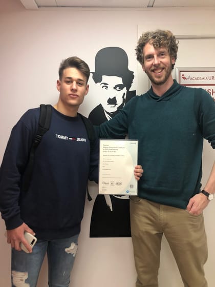 Alumno de Academia UR+ con su certificado oficial Pearson de nivel B1, junto a su profesor